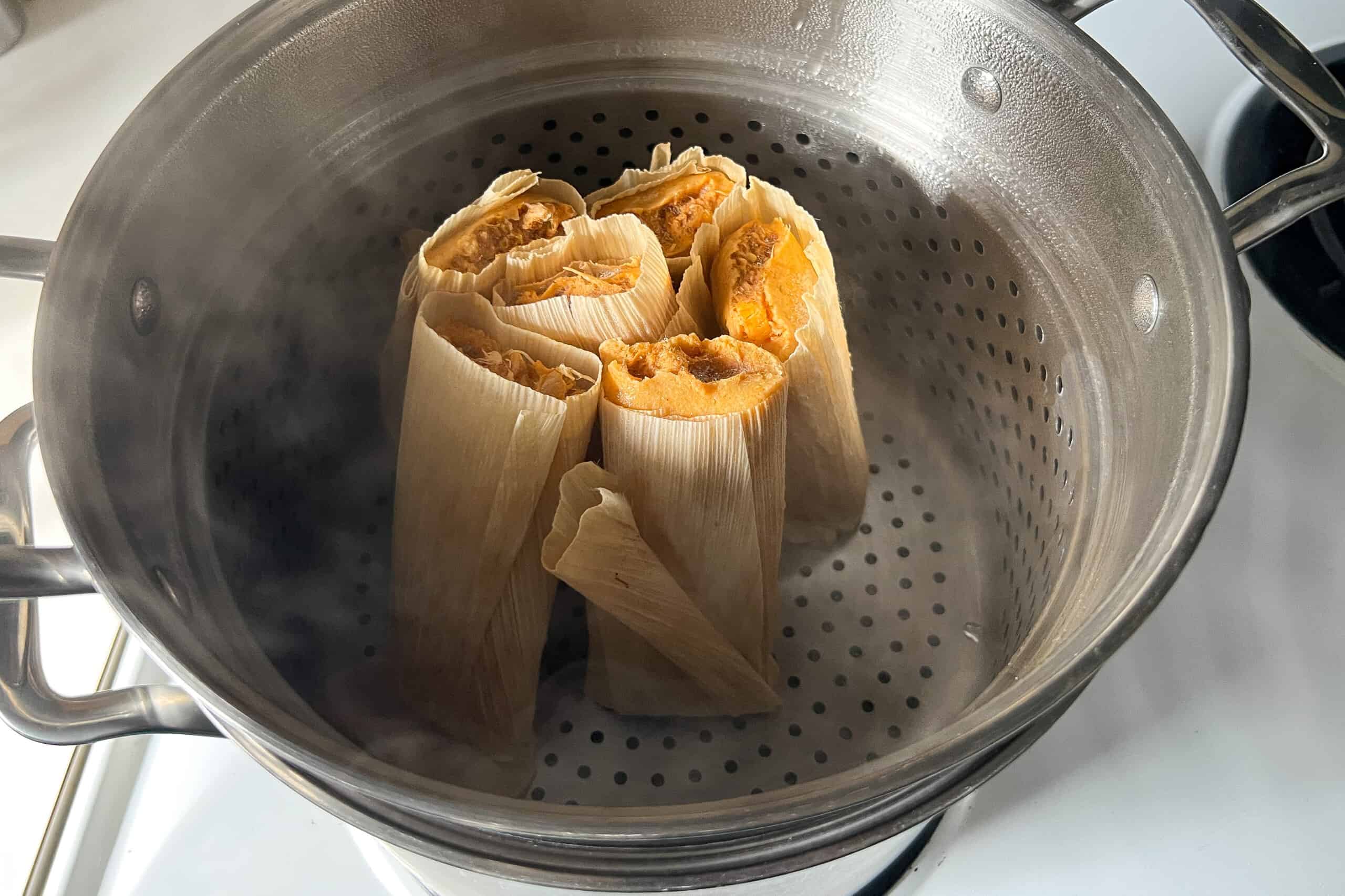 tamales placed upright in the steamer basket of a stockpot
