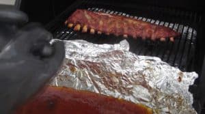 taking baby back ribs out of the foil and placing back on the foil