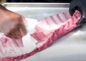removing the membrane form the back of baby back ribs with a paper towel