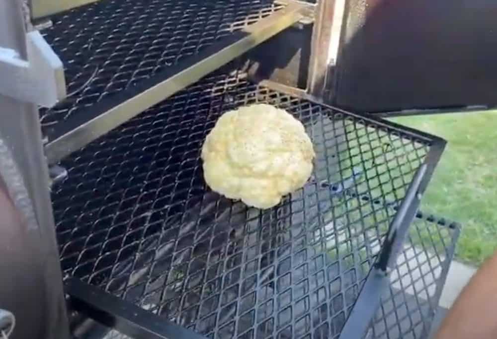 putting a head of cauliflower in a smoker