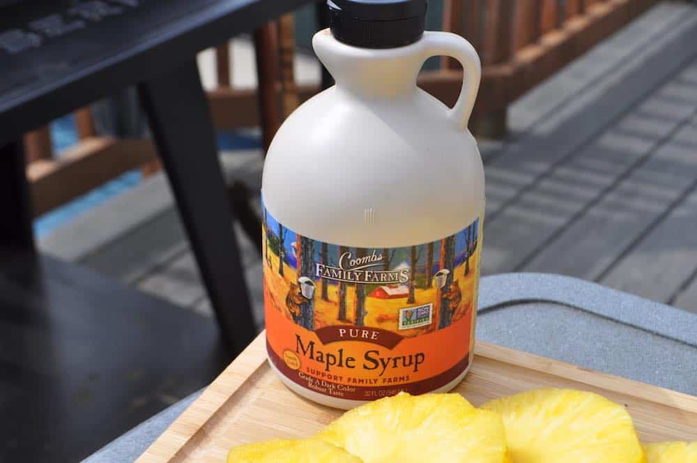 a jug of maple syrup next to some pineapple slices