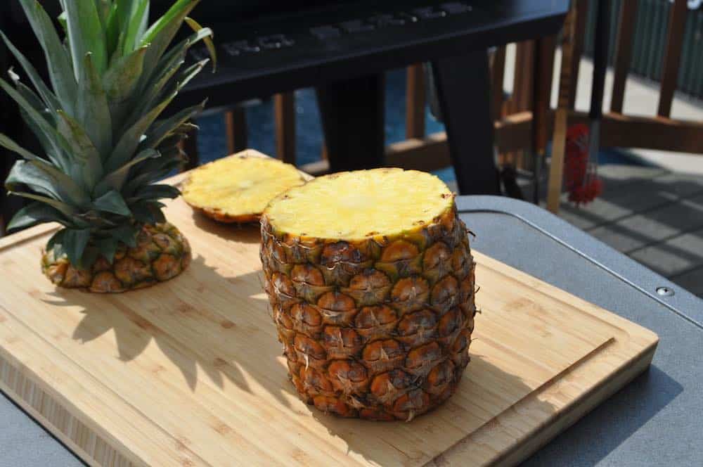 Sliced pineapple in a bowl on a cutting Board with a knife and a whole  pineapple. Stock Photo by Artem_ka2