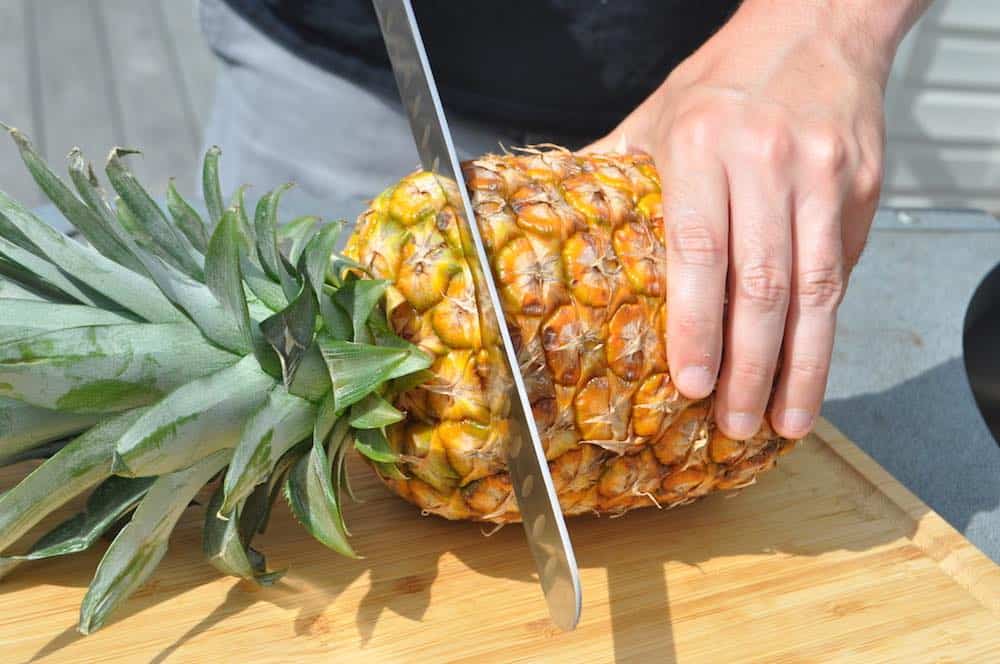 slicing the top off of a pineapple