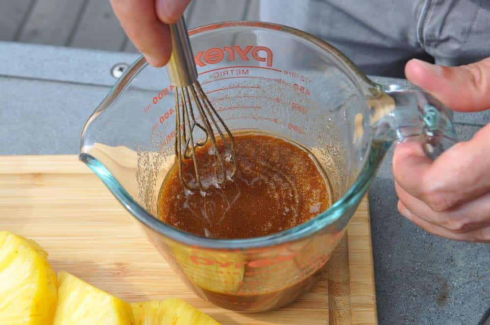 whisking together maple and brown sugar with bourbon for smoked pineapple glaze