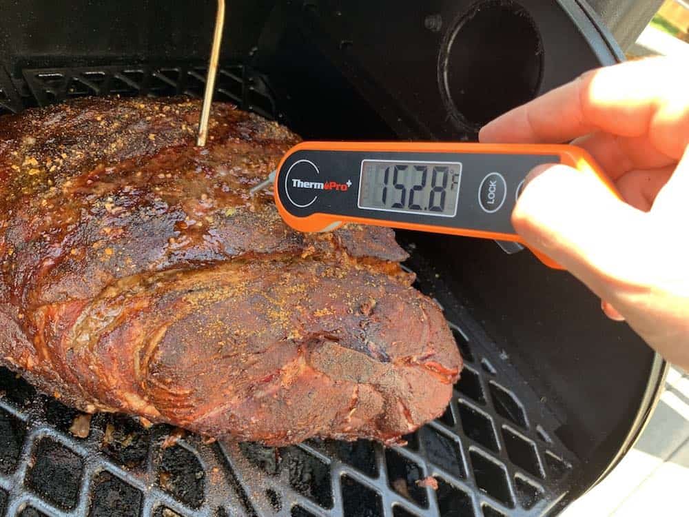 an instant read thermometer showing 152 degrees on a pit boss pork butt ready to be wrapped