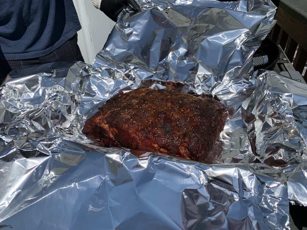 placing a pit boss pork butt in aluminum foil to wrap for the texas crutch