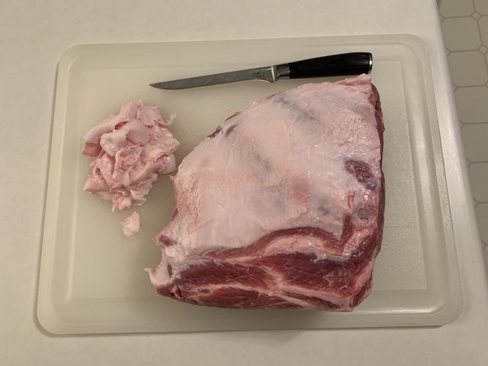 a trimmed raw pork butt on a cutting board