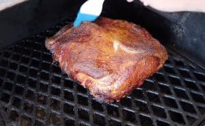 basting apple juice on to a pork shoulder vor pulled pork on a pit boss