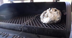 a wrapped pork butt in foil on a pit boss grill