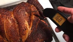 thermometer in the breast of a spatchcocked turkey showing 168 degrees