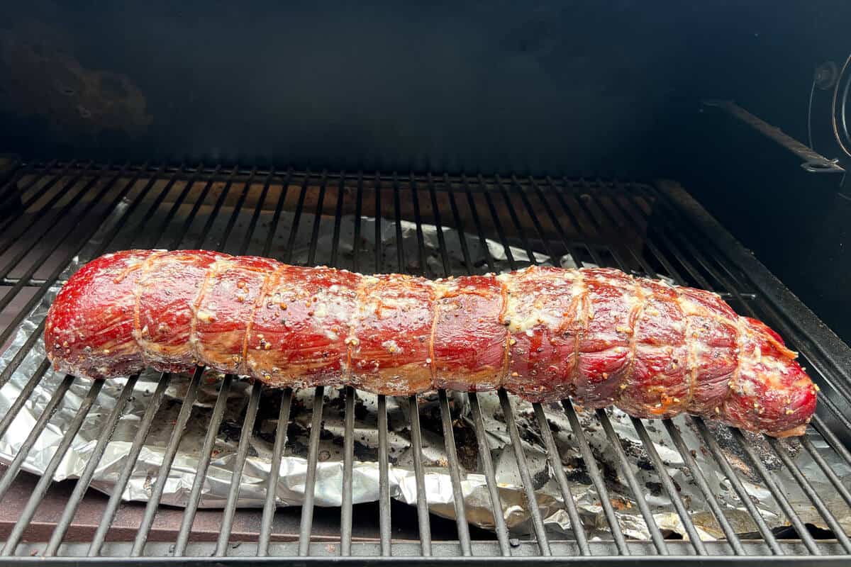 beef tenderloin smoking on the grates of a Traeger pellet grill