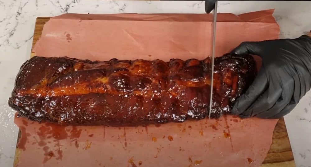 slicing up a rack of electric smoker smoked baby back ribs