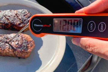 Filet mignon on a plate with an instant read thermometer reading 120 degrees F