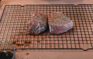 sprinkling salt and pepper on two filet mignons before smoking