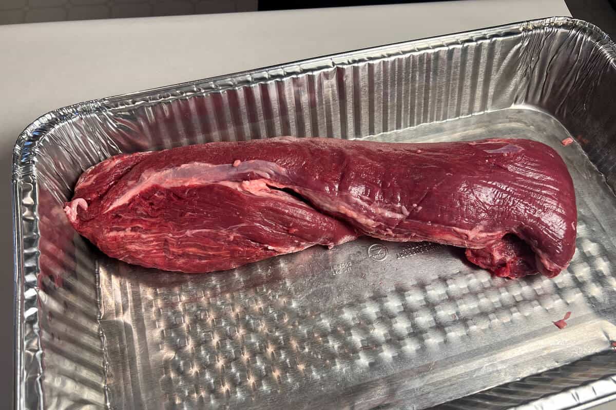 raw beef tenderloin in an aluminum foil pan