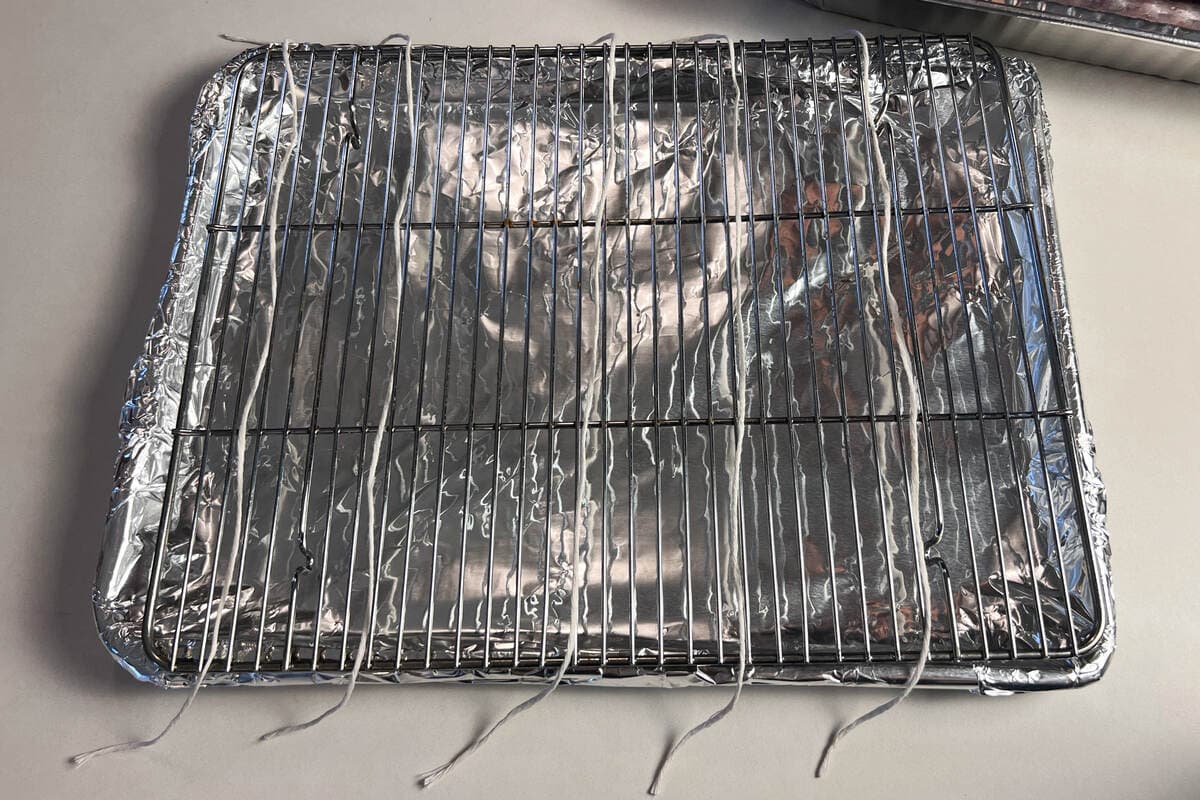 butcher twine segments laid out  on a wire rack over an aluminum foil covered baking sheet