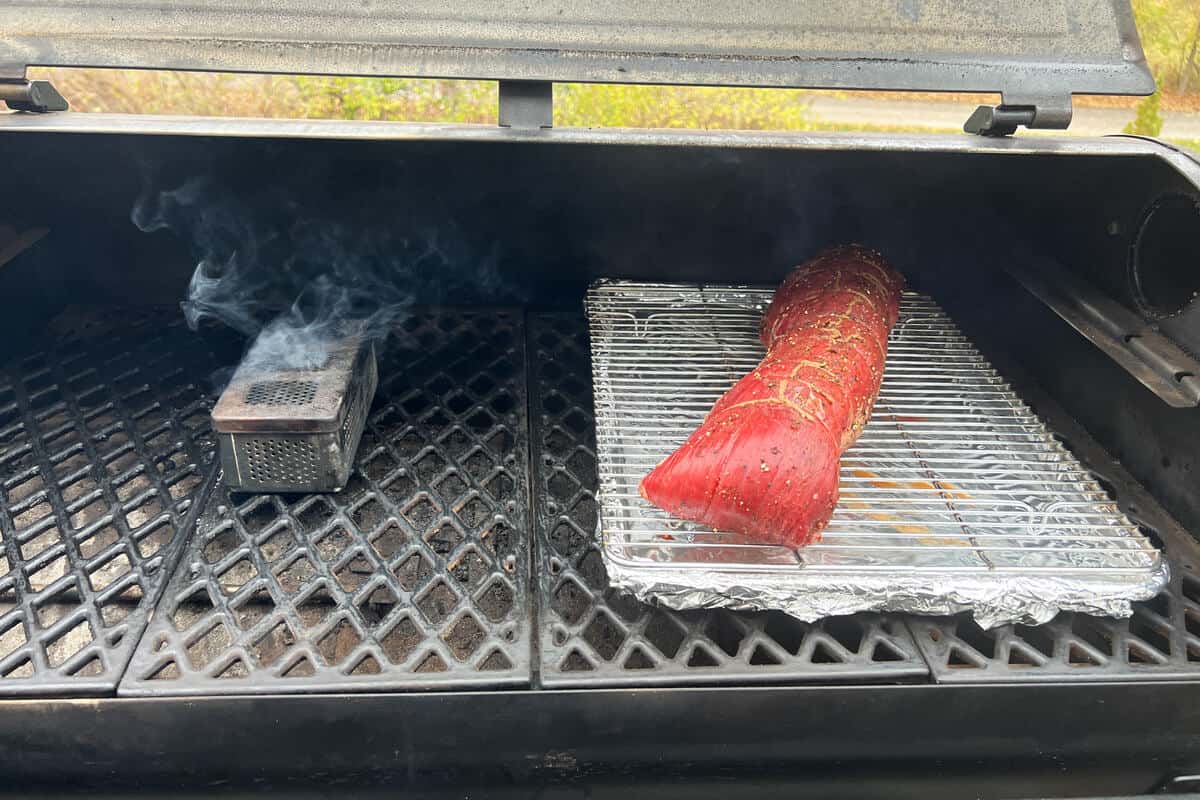 a beef tenderloin on a wire rack baking sheet combo on the grates of a pit boss pellet grill