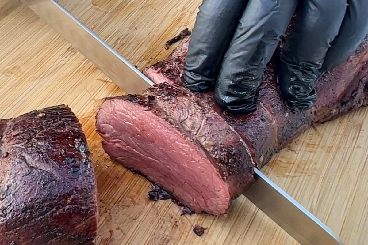 slicing into a beef tenderloin with a meat slicing knife