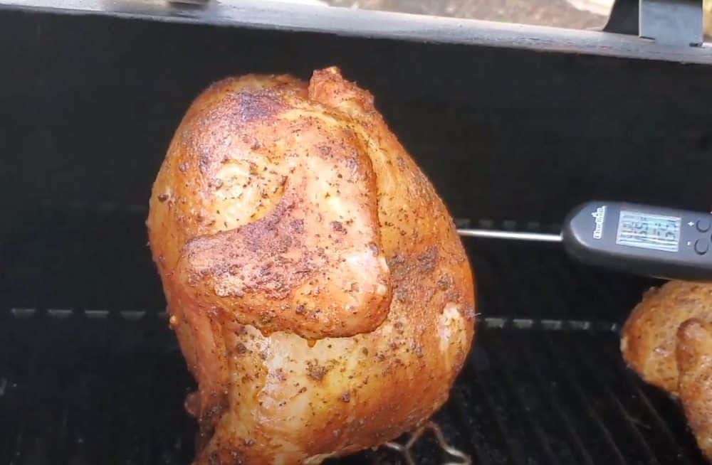 checking the temperature of a beer can chicken on a pellet grill