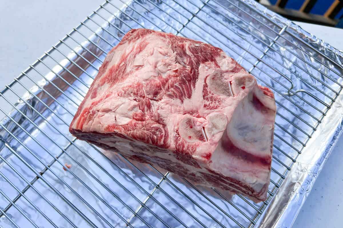 raw prime rib on a wire rack over a baking sheet