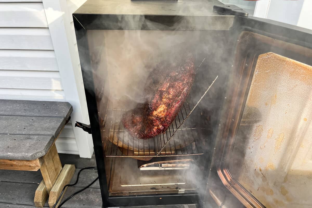 a beef brisket in a masterbuilt electric smoker with lots of smoke coming out