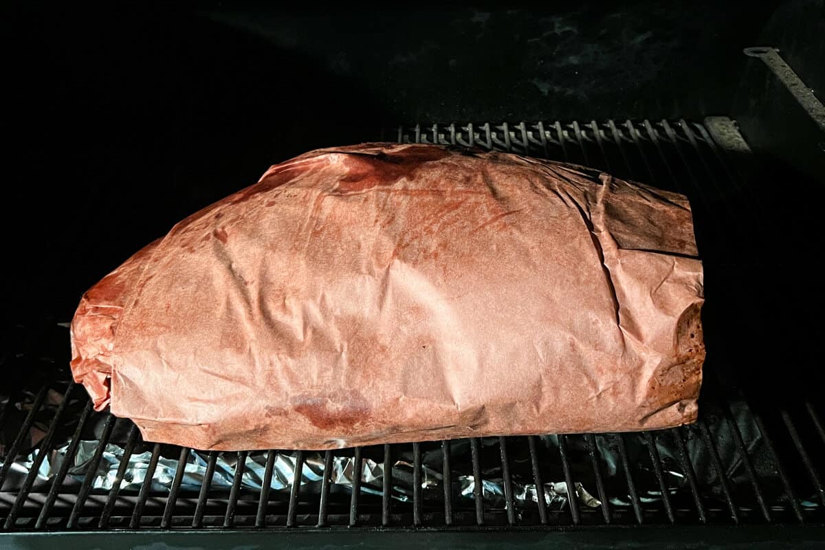 beef brisket wrapped in butcher paper on the grates of a Traeger pellet grill