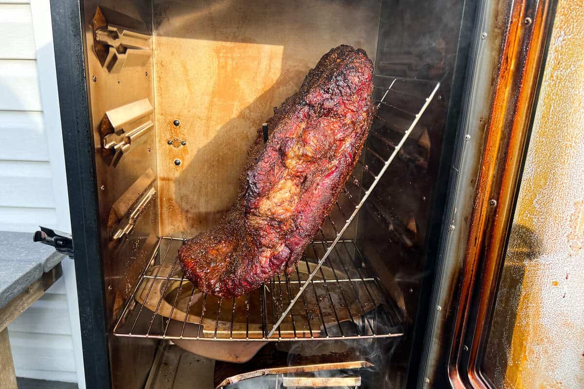 a beef brisket positioned diagonally in a masterbuilt electric smoker