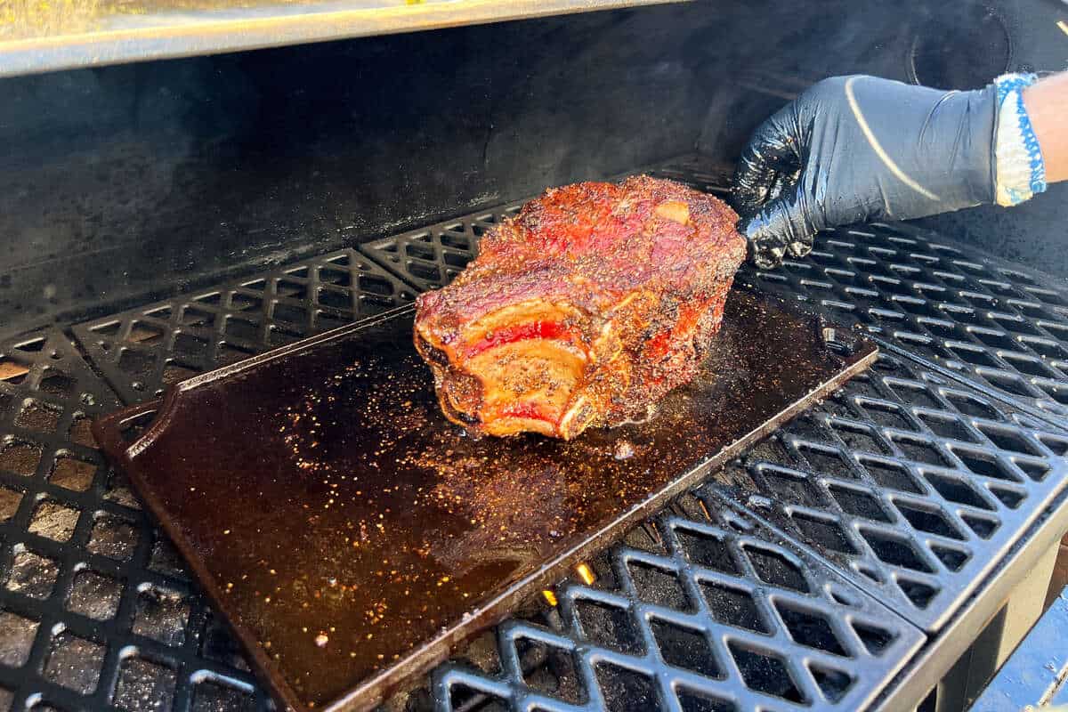 searing a prime rib roast on a cast iron griddle on the grates of a pit boss pellet grill