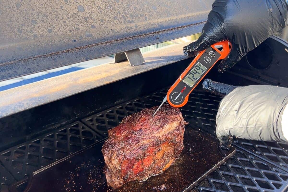 an instant read thermometer measuring the inside of a prime rib at 124.9 degrees F