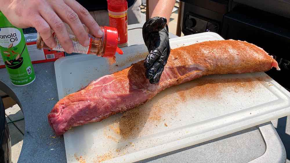 pork loin being seasoned with bbq rub