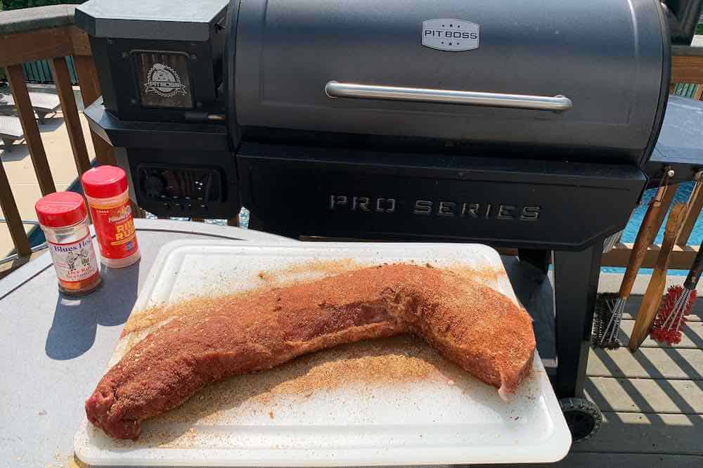 pork loin seasoned on a cutting board in front of a pit boss pellet grill