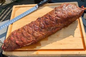 Pork loin resting on a cutting board with a slicing knife