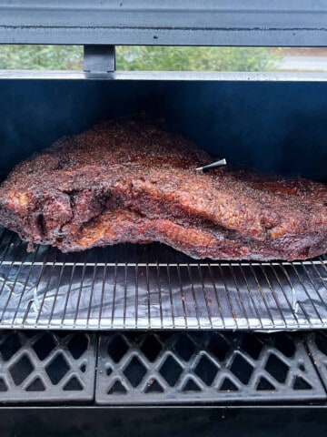 a whole packer brisket on a wire rack baking sheet combo on the grates of a pellet grill