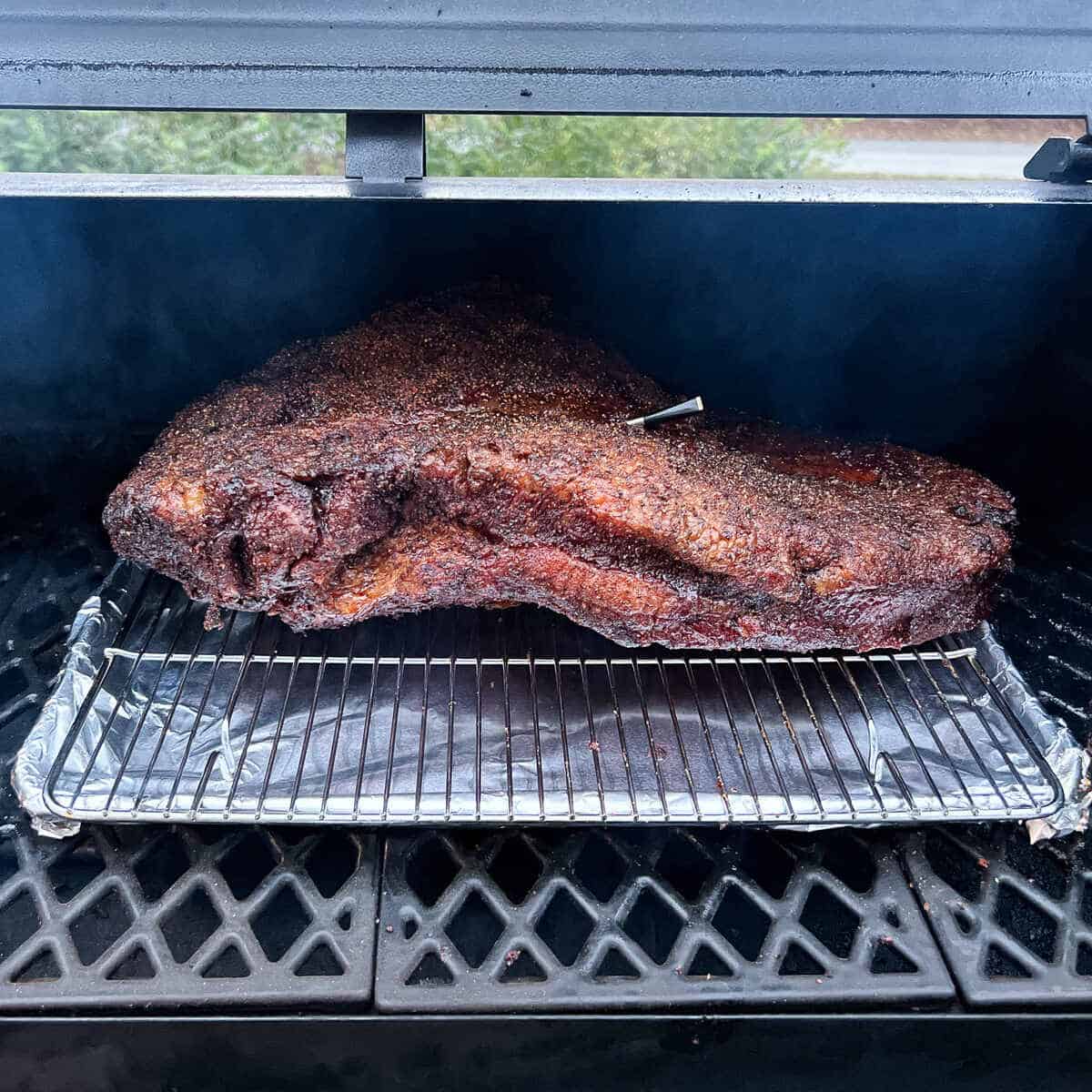 a whole packer brisket on a wire rack baking sheet combo on the grates of a pellet grill