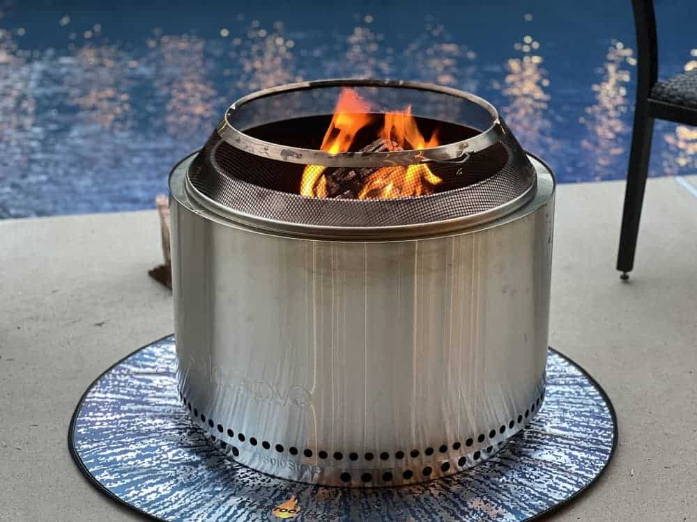 Lit Solo Stove on top of a fireproof mat on concrete by a pool