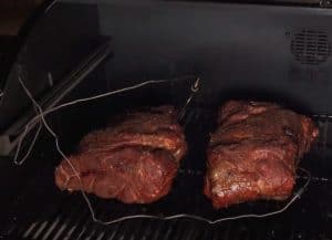 two pork butts smoking on a camp chef pellet grill