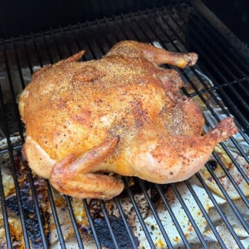 Whole chicken smoking on the grates of a Traeger pellet grill