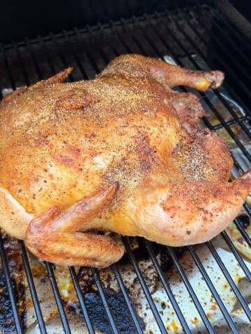 Whole chicken smoking on the grates of a Traeger pellet grill