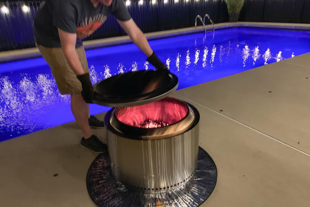Mads placing the solo stove cover on the solo stove in front of a pool