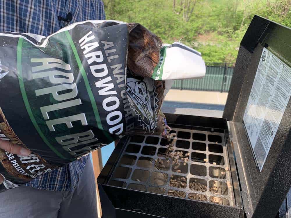 pouring apple pellets in a pit boss hopper