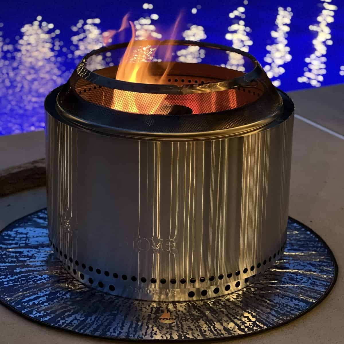 solo stove lit in front of a pool at night