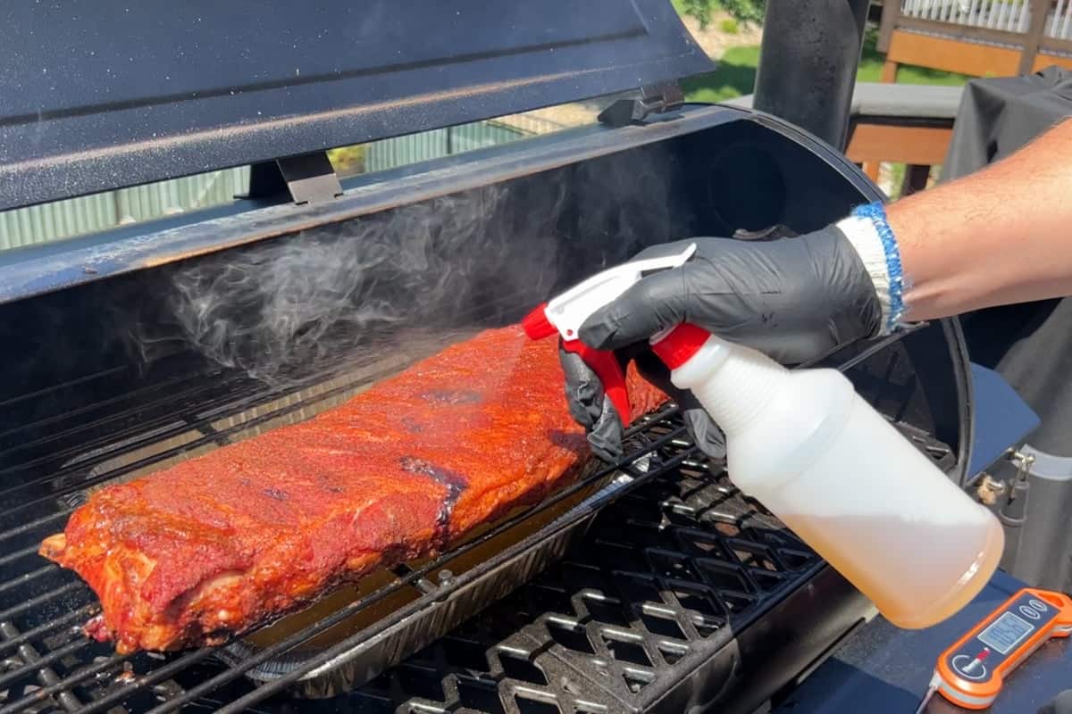 Spraying spareribs with apple cider vinegar