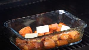 putting carrots in smoker in a dish with butter