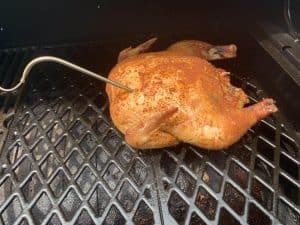 a temperature probe in a whole chicken smoking on a pit boss pellet grill