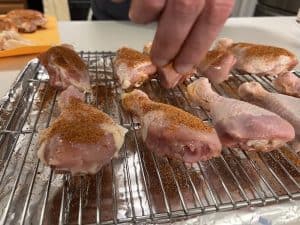 seasoning raw chicken legs before smoking on a pit boss