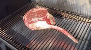 a tomahawk steak smoking on a smoker