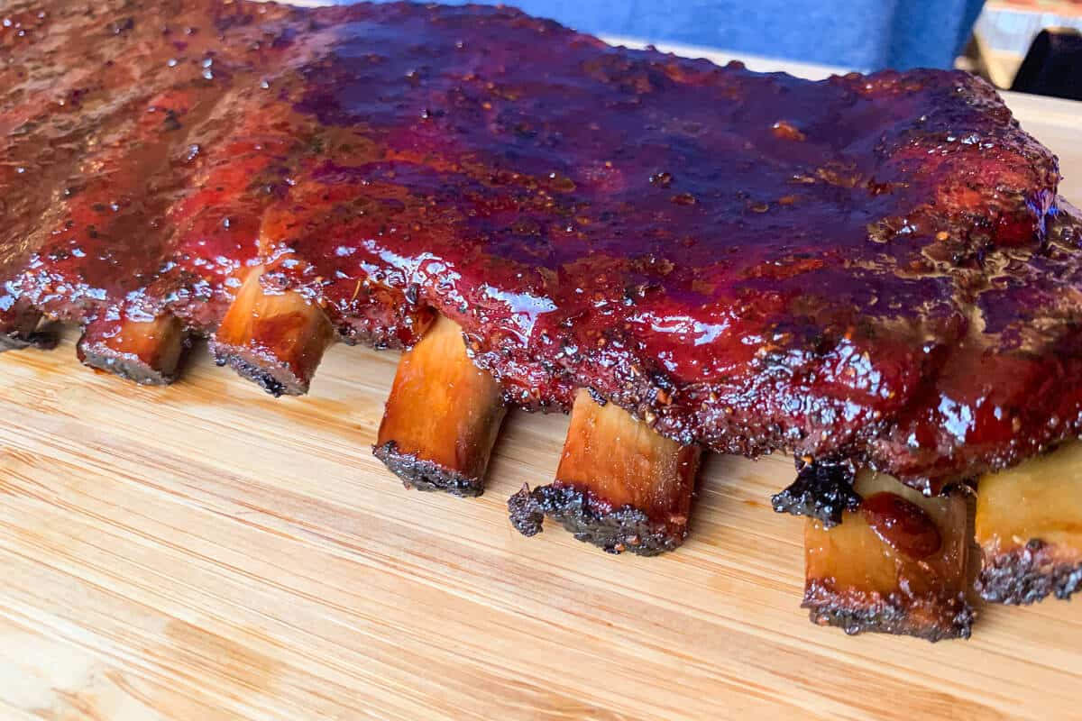 pork spare ribs on a wooden cutting board showing the meat pulling away from the bones