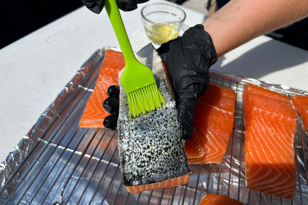 brushing olive oil on salmon skin with a silicone basting brush