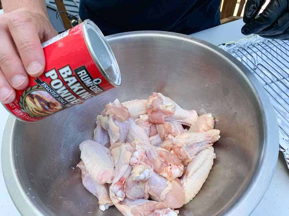 raw chicken wings in a bowl being tossed with baking powder