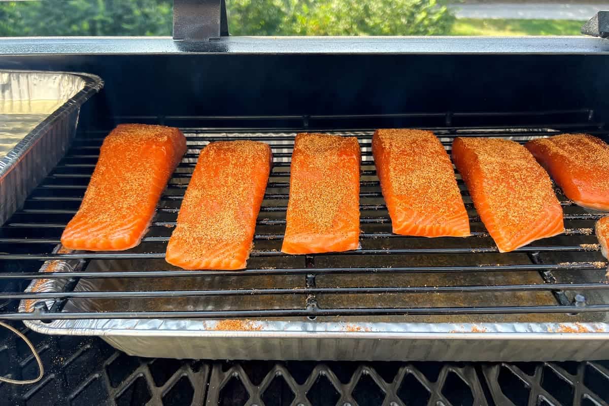 salmon fillets on the top rack of a pit boss pellet grill skin side down with seasoning on top